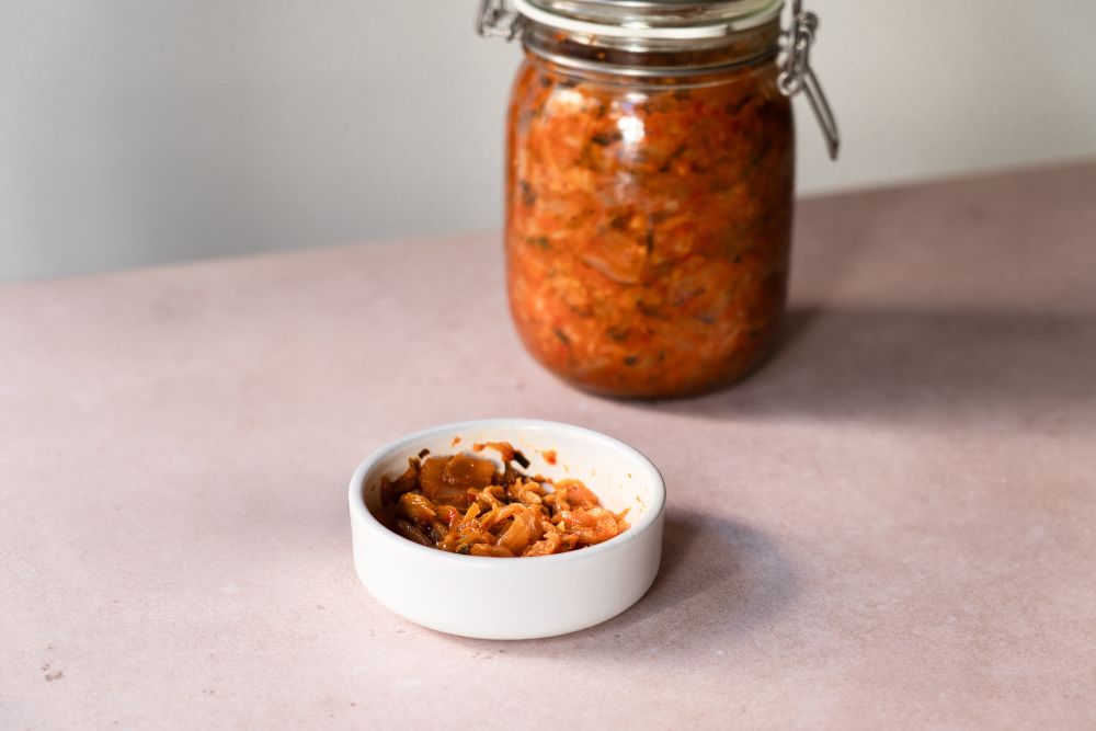Eine Schale voll Kimchi vor einem Glas Kimchi