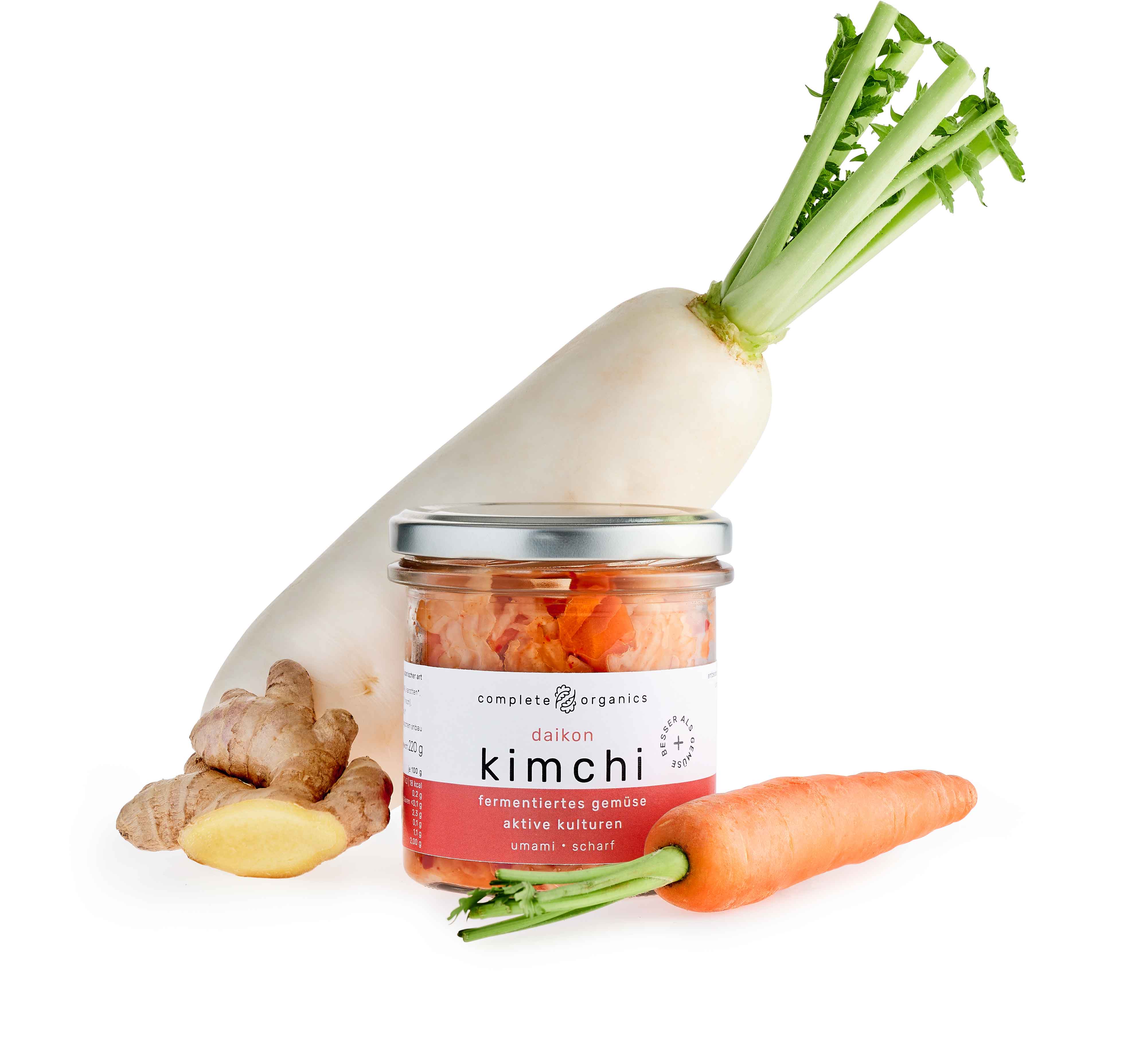 Fermentiertes Daikon Kimchi im Glas mit Rettich, Karotte und Ingwer im Hintergrund