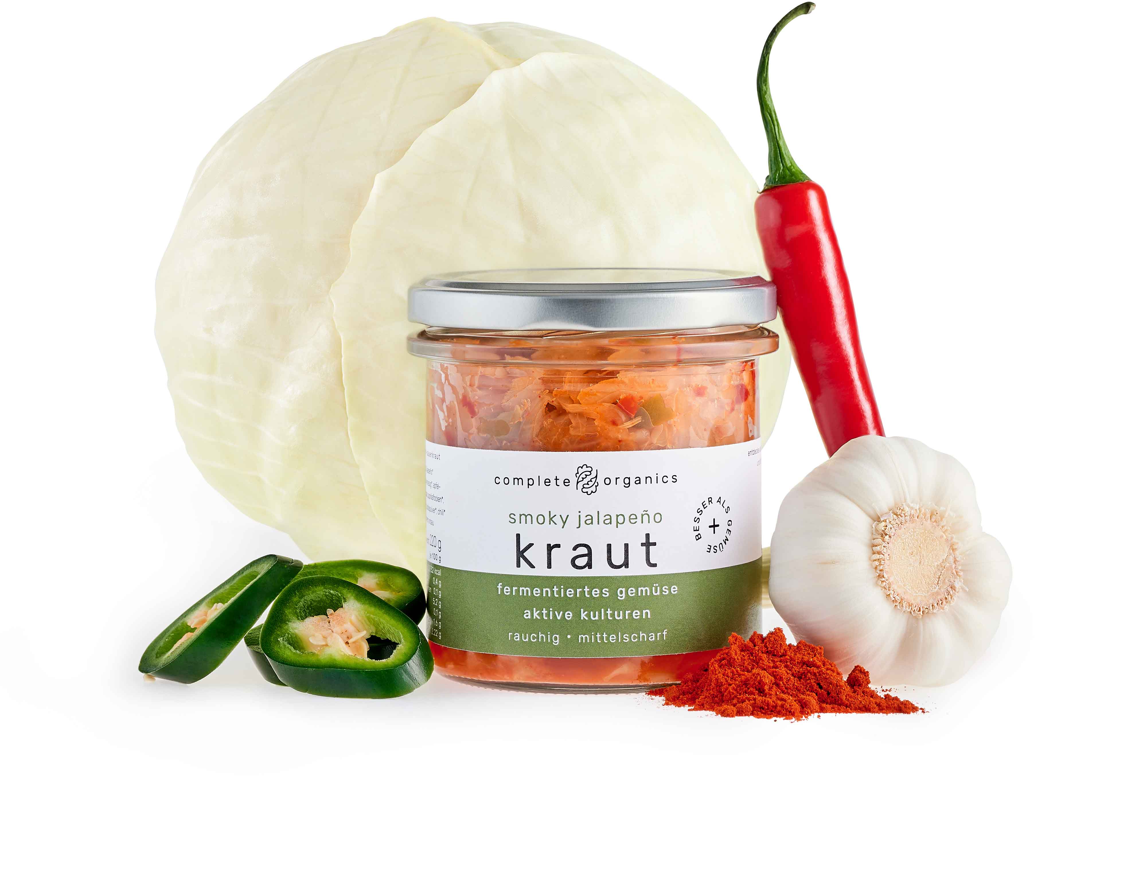 Fermentiertes Smoky Jalapeño Kraut im Glas mit Weißkohl, Jalapeño, Knoblauch, Chilischote und geräuchertes Paprikapulver im Hintergrund