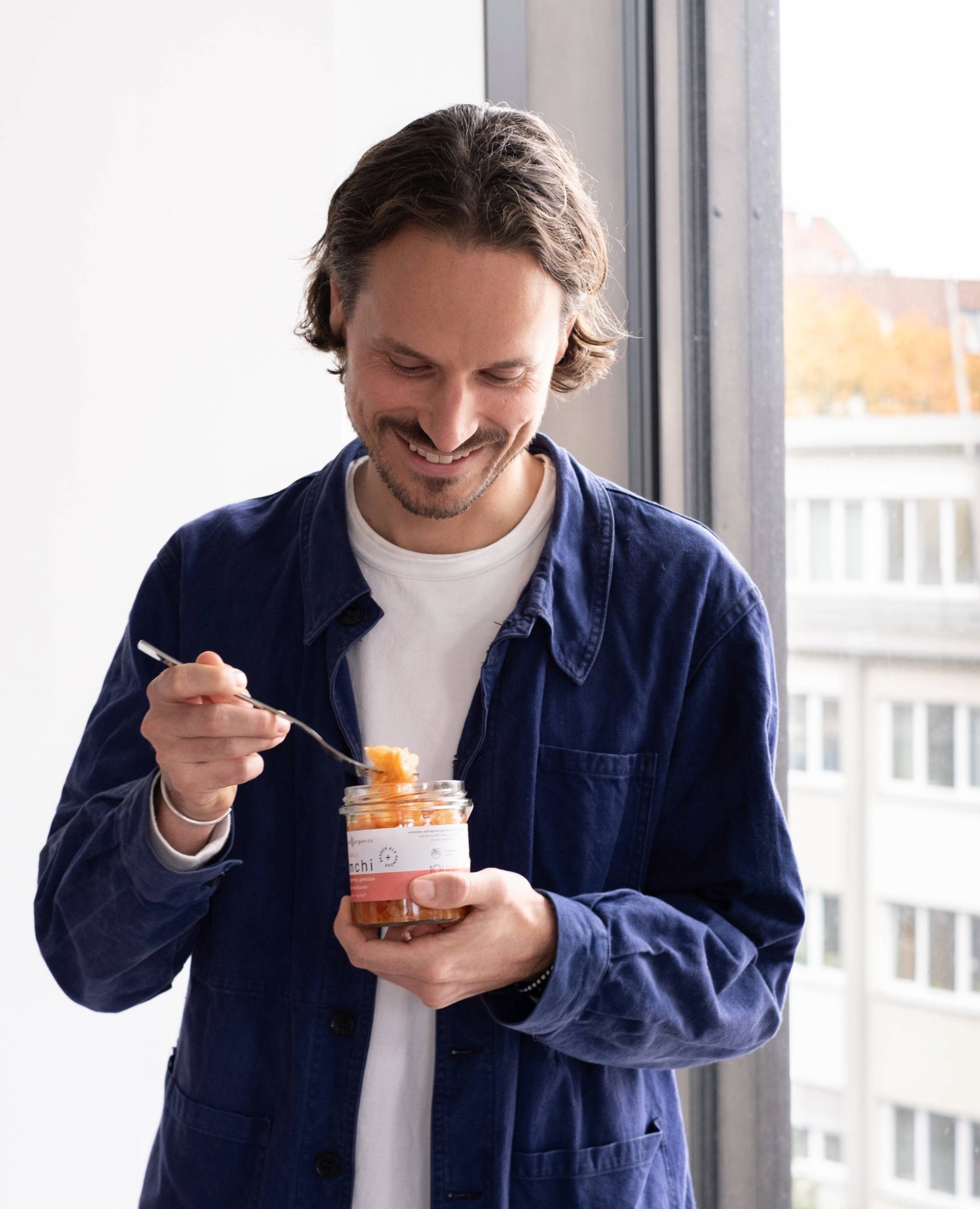 Mann hält daikon kimchi im Glas in der Hand