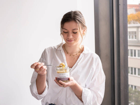 Frau hält white kimchi im Glas in der Hand